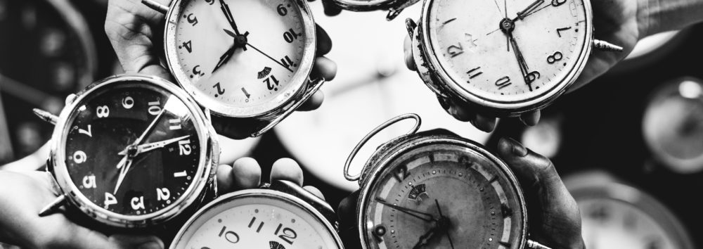 Closeup of hands holding clocks grayscale